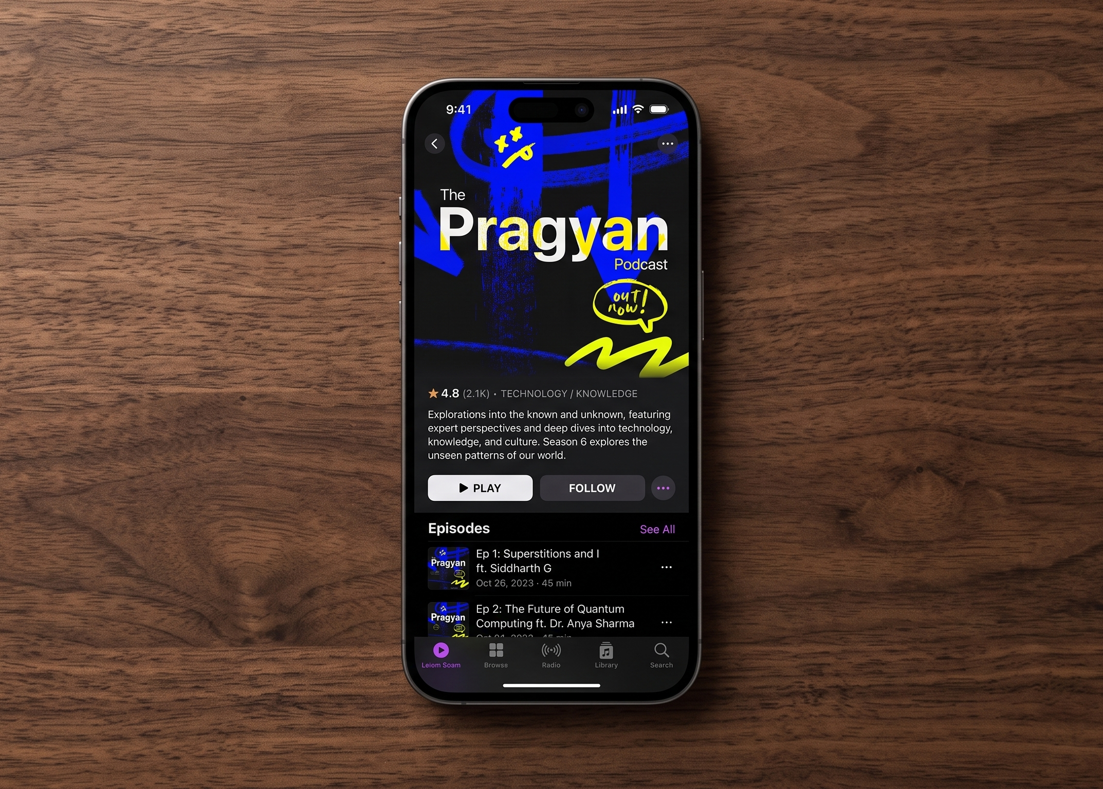 Pragyan Podcast on a phone lying on a wooden table